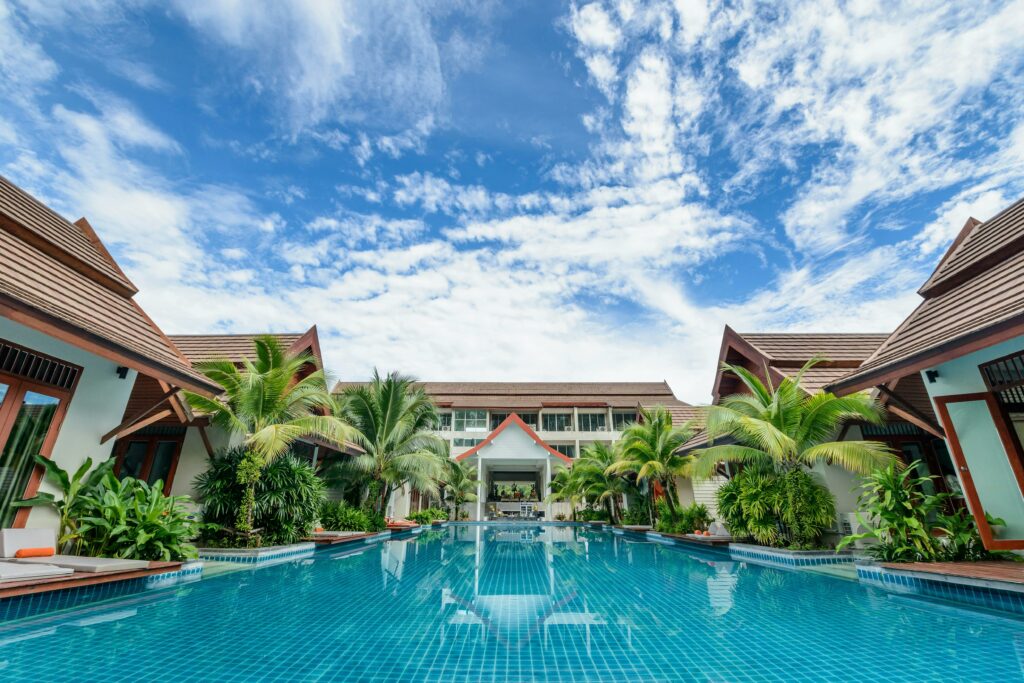 Complejo hotelero con una gran piscina en mitad de la fotografía y muchas palmeras